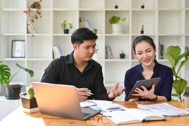 Dijital tablet kullanan ve projeyi tartışan iki genç iş arkadaşı.