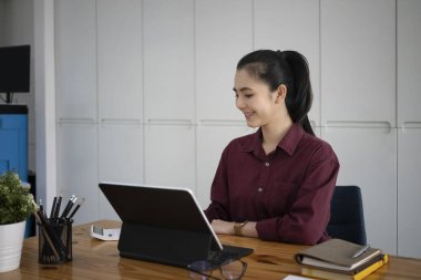 Ofisinde bilgisayar tabletiyle çalışan Asyalı çekici bir iş kadını..