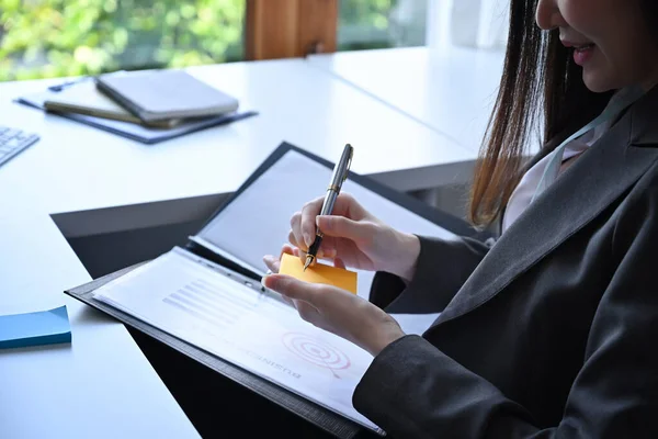 彼女のオフィスの机に座っている間 ビジネスの女性は付箋にメモを作る — ストック写真