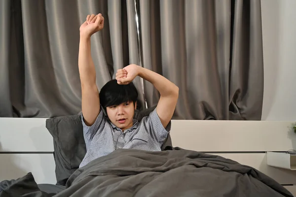 アジア系の男が目を覚まし腕を伸ばして — ストック写真