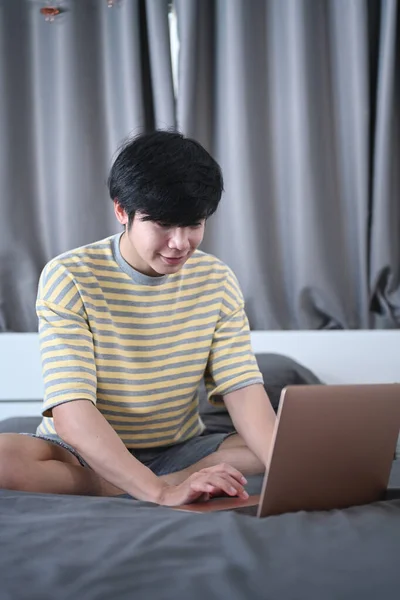 Χαμογελώντας Ασιατική Άνθρωπος Περιήγηση Στο Διαδίκτυο Φορητό Υπολογιστή Στο Υπνοδωμάτιο — Φωτογραφία Αρχείου