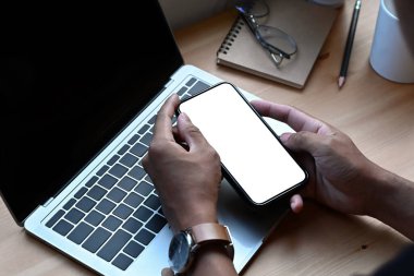 Bilgisayarın önünde oturan ve akıllı telefon kullanan iş adamını kapat..