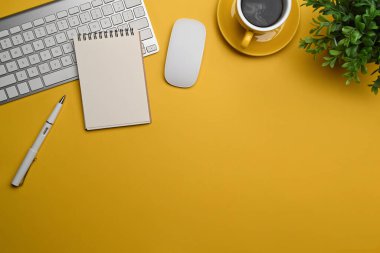 Not defteri, kahve fincanı, çiçek ve malzemeler sarı arka planda..