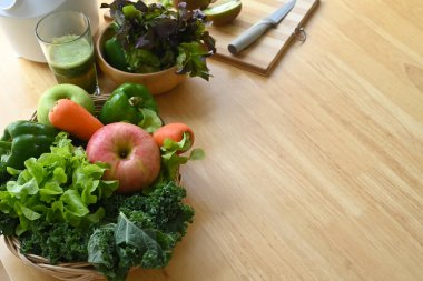 Tahta masanın üzerinde hasır sepette çeşitli organik sebzeler ve meyveler..