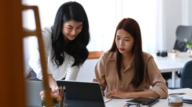 Bilgisayar tabletindeki yatırım verilerini analiz eden iki genç iş arkadaşı.