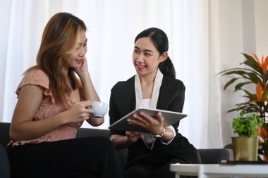 Dost canlısı Asyalı kadın sigorta acentesi kadın müşteriye hayat sigortası teklif ediyor.