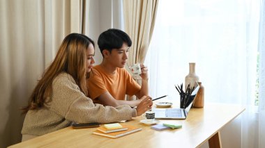 Genç Asyalı çift birlikte bilgisayar laptopundan video izliyor veya alışveriş yapıyorlar..