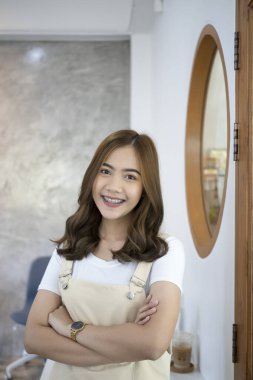 Yaratıcı ofiste kollarını kavuşturup kameraya gülümseyen neşeli Asyalı kadın portresi..