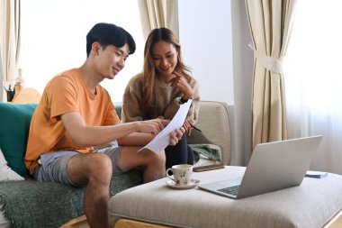 Genç çift evde faturalarını ödemek için dizüstü bilgisayar kullanıyor..