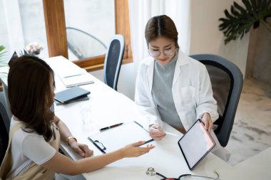 Dost canlısı doktor dijital tablet kullanıyor ve hastaya tıbbi muayene sonuçlarını anlatıyor..