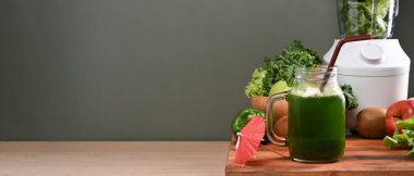 Sağlıklı yeşil sebze suyu ve ahşap masanın üzerindeki malzemeler. Vejetaryen gıda konsepti.