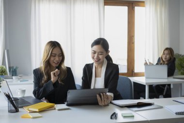 Dijital tablet kullanan ve yeni projeyi tartışan iki mutlu iş kadını..