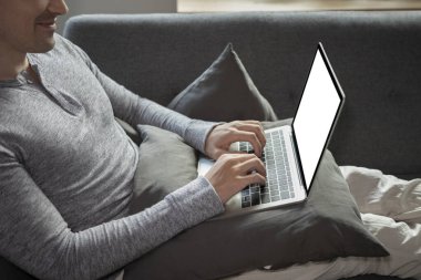 Yakışıklı adam rahat bir koltukta oturup dizüstü bilgisayarla internette geziniyor..