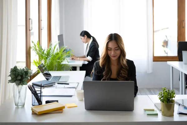 美しいビジネス女性が明るい近代的なオフィスに座って ラップトップコンピュータで作業 — ストック写真