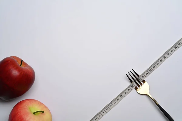 白い背景に測定テープとリンゴでフォーク 体重と健康的な食事のコンセプト — ストック写真