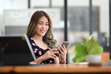 Ofiste akıllı telefon kullanan güzel Asyalı kadın..