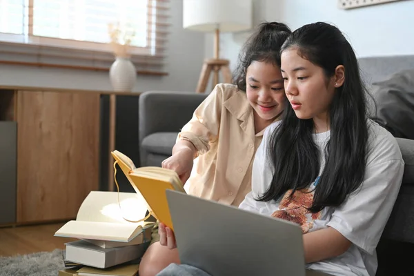 아름다운 아시아인 소녀는 거실에서 여동생 과앉아 노트북으로 인터넷 서핑을 — 스톡 사진