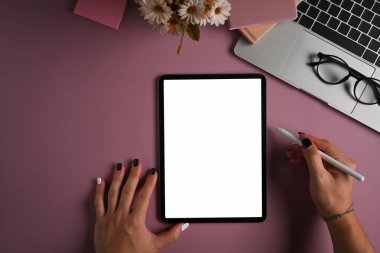 Yaratıcı kadın stilus kalem tutuyor ve mor arka planda dijital tablet kullanıyor.