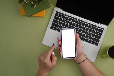Bilgisayarın önünde oturan ve cep telefonu kullanan tepeden bakan kadın..
