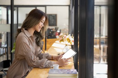 Yan görünüm güzel Asyalı kadın serbest dijital tablet üzerindeki e- postaları kontrol ediyor.
