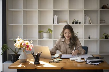 Modern iş yerinde bilgisayar laptopuyla çalışan muhteşem genç bir iş kadını..