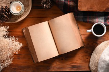 Kaliteli kitap, bir fincan kahve ve ahşap arka planda mum..