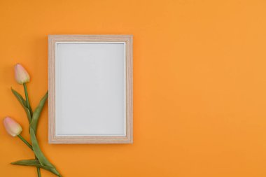 Boş ahşap çerçeve ve sarı arkaplanda pembe laleler.