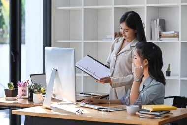 Asyalı kadın yönetici, stajyer meslektaşlarına finansal operasyonlar hakkında danışmanlık yapıyor..