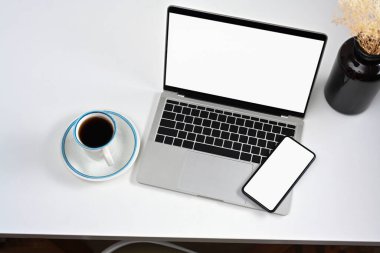 Mockup dizüstü bilgisayar, akıllı telefon ve beyaz masada kahve fincanı..