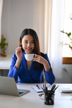 Ofis masasında kahve içen hoş genç bir iş kadını..