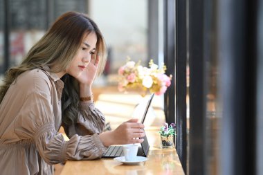 Cafede bilgisayar tabletleriyle çalışan Asyalı çekici kadın tasarımcı..