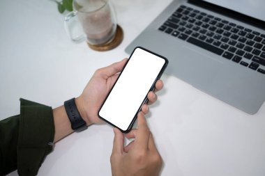 Bilgisayarla çalışan ve ofis masasında akıllı telefon kullanan bir iş adamı..