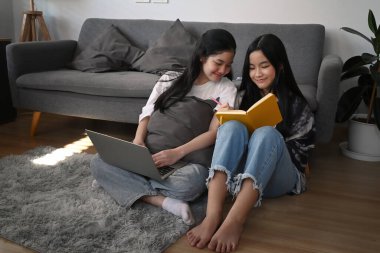 İki Asyalı genç öğrenci oturma odasında otururken birlikte ödev yapıyorlar..