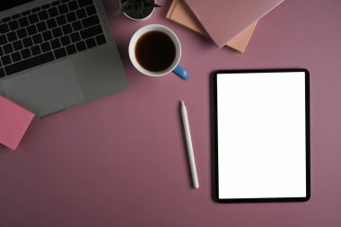 Dijital tablet, stilus kalem, dizüstü bilgisayar ve mor arka planda kahve fincanı..