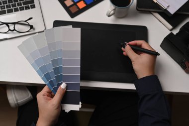 Renk örnekleri taşıyan ve grafik tabletle çalışan yaratıcı kadın.