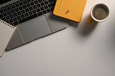 Düz dizüstü bilgisayar, defter ve kahve beyaz ofis masasının üzerinde duruyordu..