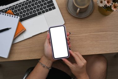 Sıradan bir adam dizüstü bilgisayarın önünde oturuyor ve akıllı telefon kullanıyor..