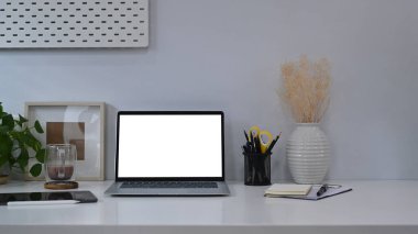 Model bilgisayar, ev bitkisi ve resim çerçeveli ofis masası.