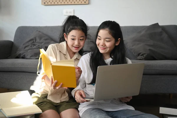 거실에 앉아서 노트북을 사용하는 아시아 소녀와 여동생의 — 스톡 사진