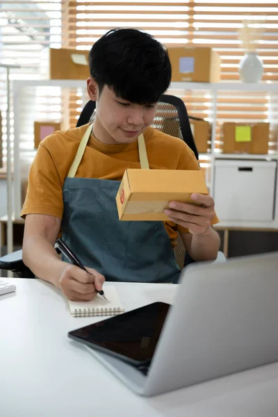 남자가 노트북 컴퓨터의 주문을 확인하고 배달용 소포를 준비하는 — 스톡 사진