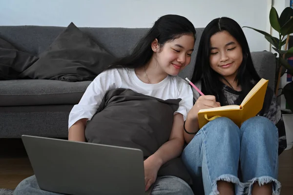 两个笑着的亚洲女孩在客厅里上网或用笔记本电脑做作业 — 图库照片