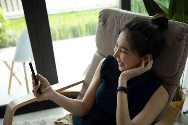 안락의자에서 편안히 쉬면서 스마트폰으로 비디오 통화를 — 스톡 사진