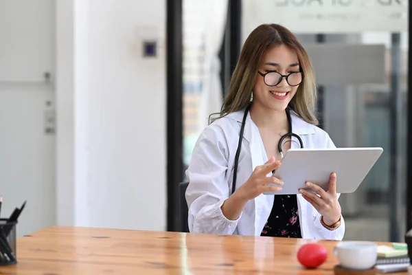Médica Encantadora Uniforme Branco Usando Tablet Digital Enquanto Está Sentada — Fotografia de Stock