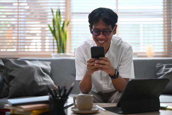 미소짓는 이시아인 가집에 스마트폰으로 네트워크를 확인하는 — 스톡 사진