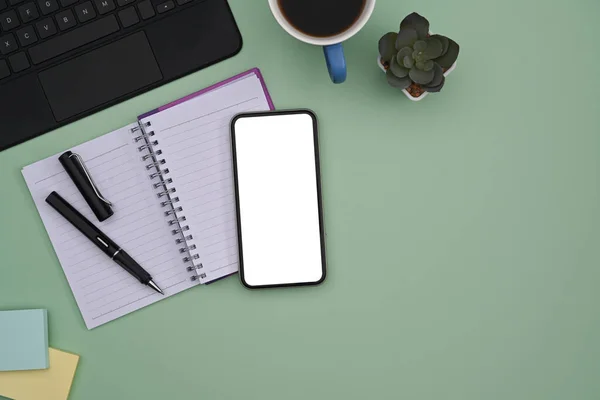 緑のパステルカラーの背景に空白の画面 ラップトップ ノートブック コーヒーカップ付きのスマートフォン — ストック写真