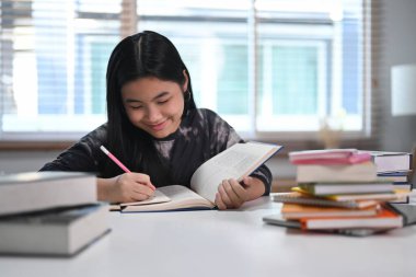 Oturma odasında ödev yapan sevimli Asyalı kız. Eğitim kavramı.