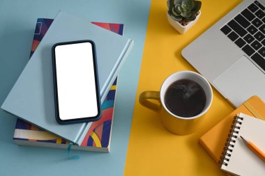 Akıllı telefon, kitaplar, kahve fincanı ve renkli arka planda dizüstü bilgisayar gibi. Üst görünüm.