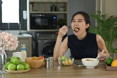 Güzel genç bir kadın taze organik vejetaryen salatası yiyor..