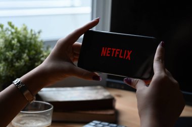 Chiang Mai, Tayland - Mar 01.2022: Netflix logolu iPhone 11 Pro Max tutan kadın. Netflix, dünya çapında bir dizi ve film sağlayıcısıdır..