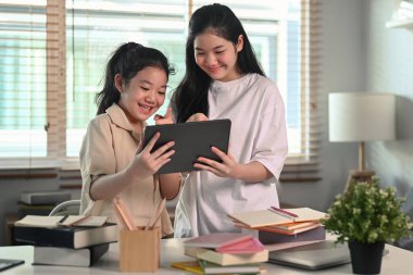 İnternette ödev yapan iki Asyalı kız ya da evde dijital tabletle internette sörf yapan..